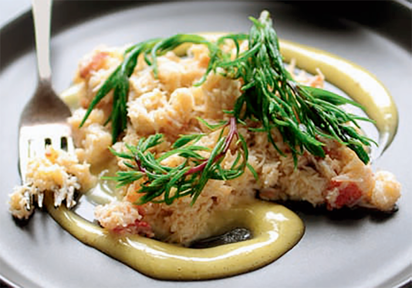 crab on a bed of vanilla mayonnaise garnished with sea blite with a fork