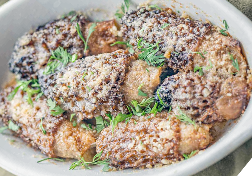seafood stuffed morels topped with parmesan cheese in a white baking dish
