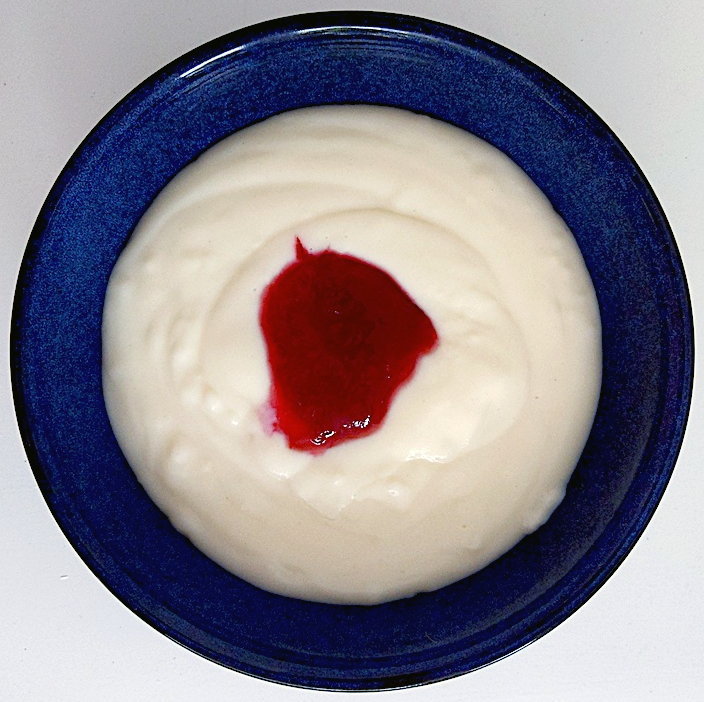semolina porridge served in a blue bowl with a dollop of red jam