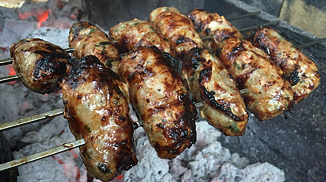 sheftalia sausages threaded on metal skewers and cooked over hot coals