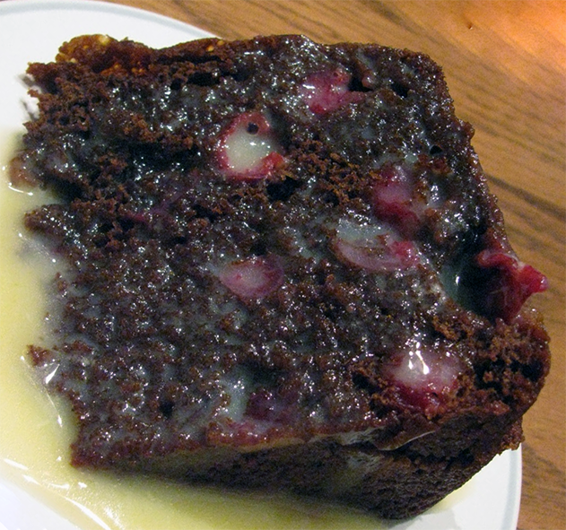 Steamed cranberry pudding with treacle on a plate with white sauce