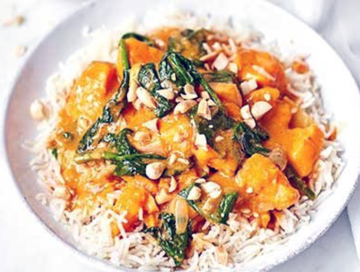sweet potato and peanut curry with spinach served on a bed of rice