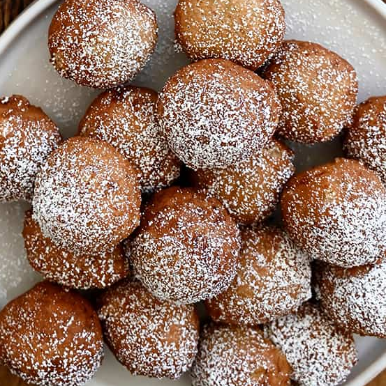 Ivorian fried banana fritters dusted with icing sugar and served on a plate