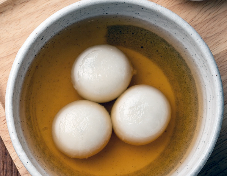 Three rice balls in syrup served in an earthenware bowl
