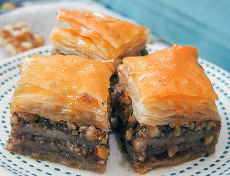 three squares of turkish Cypriot baklava with walnut and pistachio filling arranged on a plate
