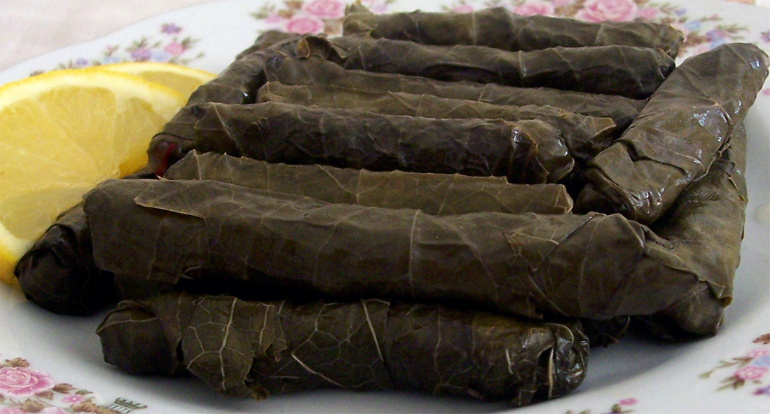 yalanci dolma, turkish cypriot stuffed vine leaves mounded on a plate with lemon slices