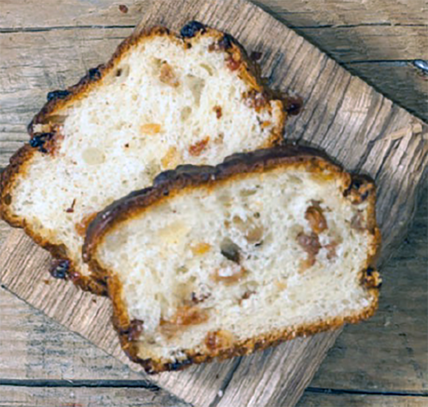 two slices of Irish tea brack, a light fruited loaf, arranged overlapping on a wooden board