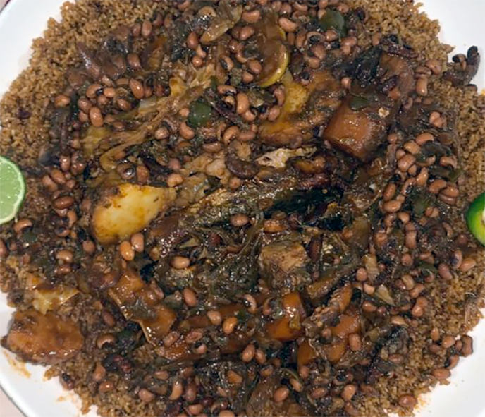 Senegalese thiebou kethaiakh, a one-pot dish of rice, fish, beans and pumpkin with cassava served on a plate with lime wedges