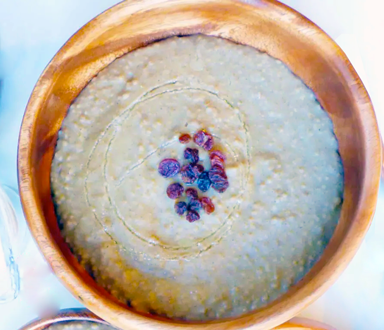 thiere ak sow, millet in cheese curds served in a wooden bowl with a berry garnish