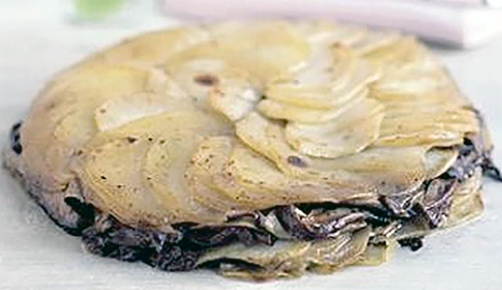 two layers of thinly-sliced potatoes with a filling of wild mushrooms on a board