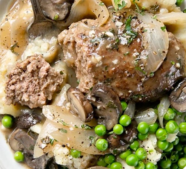 Salisbury steak on a bed of mashed potatoes with onions topped with a mushroom and onion gravy