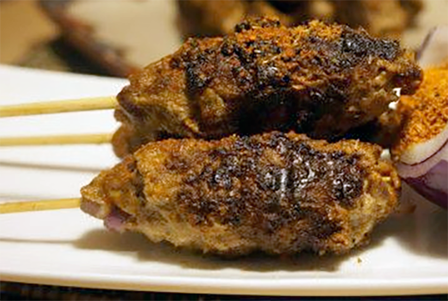 two spicy minced meat kebabs served with a half onion filled with suya dipping spice