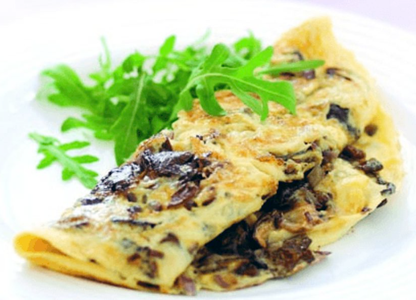 omelette folded over a wild mushroom filling served on a white plate with rocket leaves